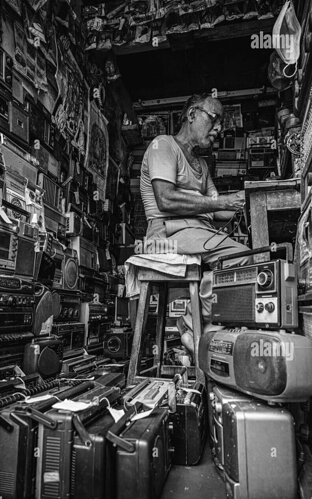 photo-en-echelle-de-gris-d-un-ancien-mecanicien-reparant-une-radio-dans-son-atelier-2htewr1